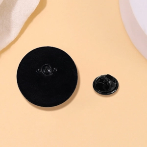 Detail view of the black round cat enamel pin back with a secure butterfly clutch fastener