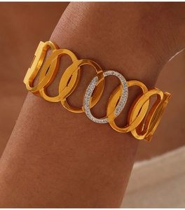 Detailed close-up of a wide gold chain bracelet with a sparkling crystal link