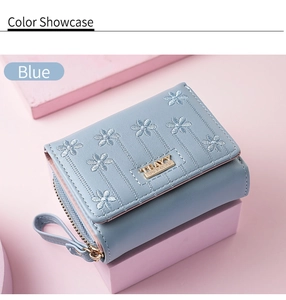 Detail of light blue leather wallet with floral embroidery and gold zipper closure
