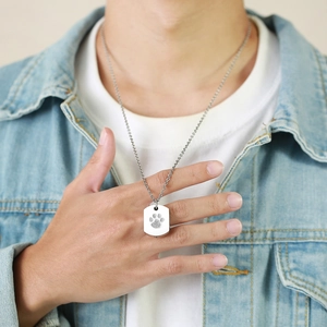 Detail of silver rectangular stainless steel paw print pendant necklace worn by male model
