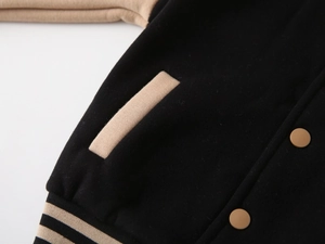 Macro detail of toddler baseball jacket featuring beige pocket stitching and button snap