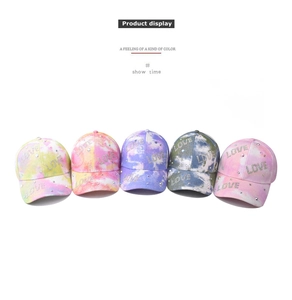 Detail view of five tie-dye baseball caps with LOVE rhinestone patterns on white background