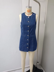 Dettaglio dell'abito smanicato in denim blu con bottoni in metallo e scollo rotondo