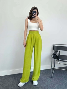 Détail du pantalon taille haute vert fluo montrant le drapé et le tissu texturé léger