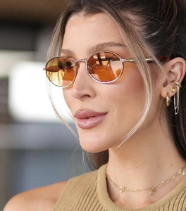 Detail of retro oval metal sunglasses with orange gradient lenses on female model