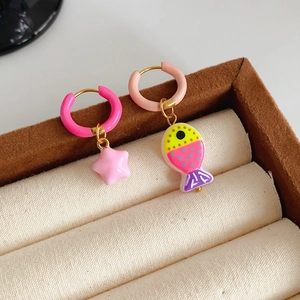 Detailed shot of cute pink star and colorful fish asymmetrical earrings on jewelry box