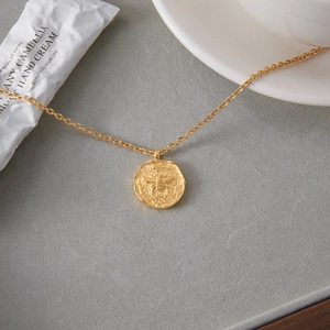 Elegant 18K gold plated coin pendant necklace with bee and moon relief on gray surface