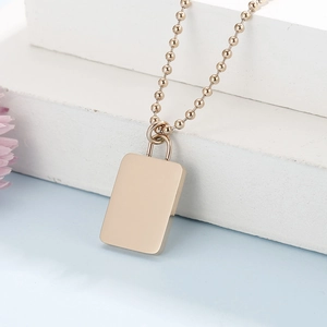 Macro shot of rose gold rectangular pendant with bead chain on white stone display