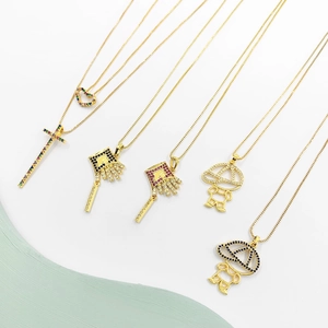Gros plan de colliers plaqués or avec pendentifs croix, cœur et zircons colorés