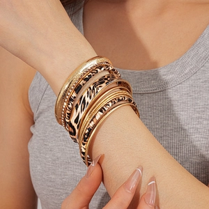 Detail of leopard print and gold metal stacked bracelets worn on a model wrist