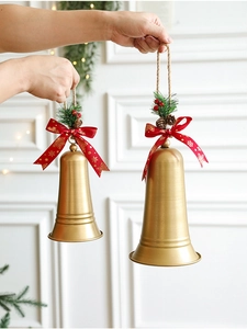 Hand holding two different sizes of gold Christmas iron bells with festive ribbons