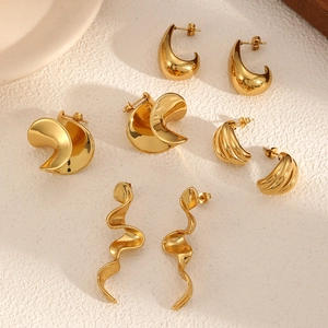 Golden geometric irregular titanium steel earrings set on white stone surface