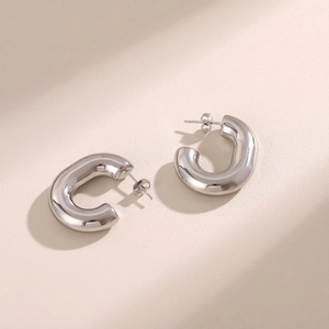 Minimalist silver C-shaped hollow stainless steel stud earrings on beige background