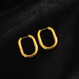 Detailed view of polished gold oval hoop earrings with a secure clasp on black velvet