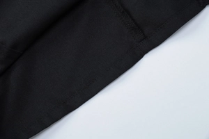 Close-up of the professional stitching and black plain weave fabric texture on the shirt