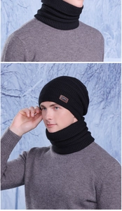 Dettaglio del set berretto e scaldacollo in maglia nera con toppa in pelle sulla neve