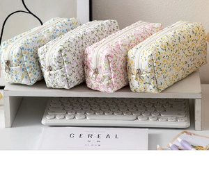Detailed view of four floral quilted stationery bags organized on a white desktop shelf