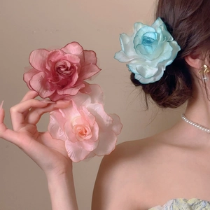 Macro detail of layers of delicate fabric flower hair clips in pink and light blue shades