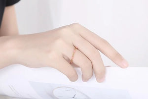 Delicato anello a catena dorata da donna con piccole perle rosa su fascia minimalista