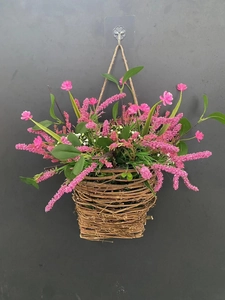 Detail of a handmade wicker wall basket with pink wildflowers and green foliage