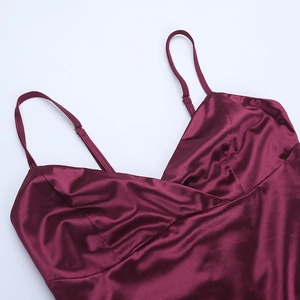 Close-up detail of burgundy satin dress showing glossy silk texture and delicate V-neckline