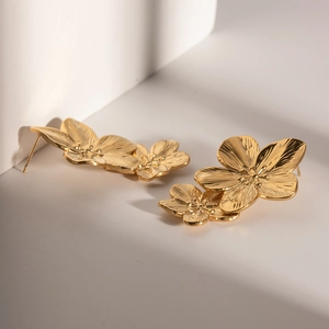Macro detail of gold double flower earrings with textured petals and metallic luster