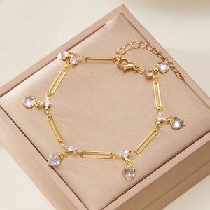 Gold chain bracelet featuring sparkling round diamonds and iridescent heart charms in a box