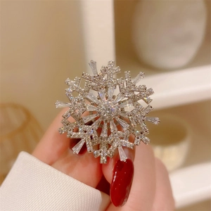 Macro shot of silver rotating snowflake brooch with sparkling zircons held by hand