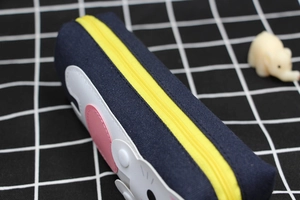 Close-up of navy canvas pencil case featuring yellow zipper and cute cat ear details