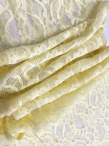 Detailaufnahme von hellgelbem Spitzenstoff mit filigranen Blumen- und Schnörkelmustern