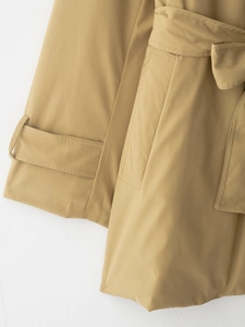 Détail de la ceinture à la taille et des pattes de serrage aux poignets du trench-coat khaki