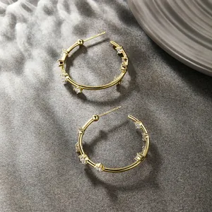 Macro shot of 14K gold-plated C-shaped hoop earrings with sparkling zircon stones