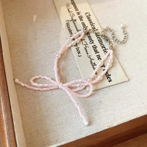 Détail du collier à nœud rose avec perles fantaisie et fermoir mousqueton argenté