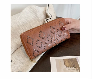 Nahaufnahme einer braunen Vintage-Lederclutch mit silbernen Nieten im Rautenmuster