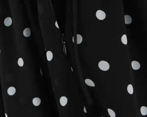 Detail eines verdeckten Reißverschlusses an einem schwarzen gepunkteten Chiffonkleid