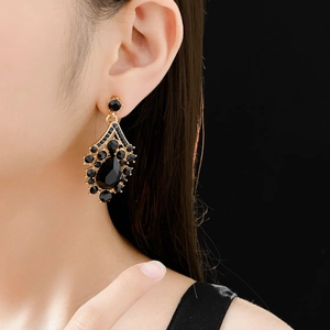 Detailed view of teardrop black gemstone earring with gold base on a model wearer