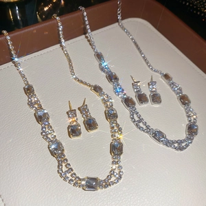 Close-up of vintage square pendant necklace and earring sets in gold and silver finish
