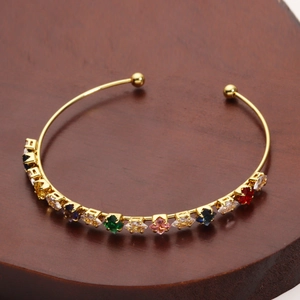 Detail of gold-plated open bangle featuring vibrant multicolor cubic zirconia gemstones