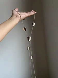 Detail of silver long sweater necklace with vertical striped metal disc pendants