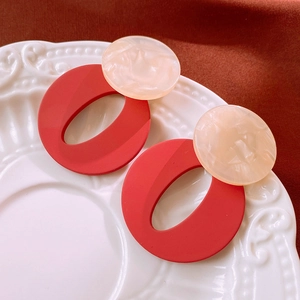 Close-up of geometric acrylic earrings with red and cream marbled resin details