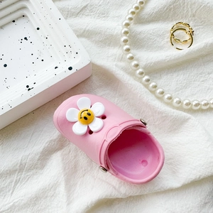 Macro detail of pink mini clog phone grip featuring a white smiley flower on fabric