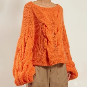 Detailed view of bright orange cable knit sweater featuring soft mohair texture