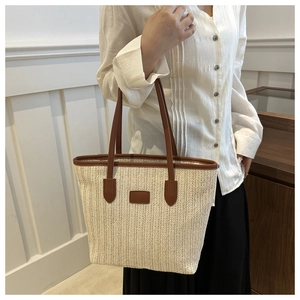Handwoven straw tote bag with brown leather handles and vintage herringbone texture pattern