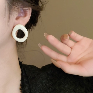 Close-up of white resin irregular geometric hoop earring worn by a model