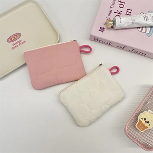Close-up of quilted heart-shaped coin purses in pink and cream with zipper detail