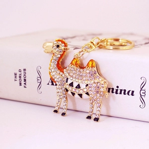 Gold camel keychain with sparkling rhinestones and orange enamel details on white book