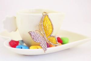 Macro detail of yellow butterfly keychain with enamel wings and sparkling crystal rhinestones