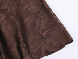 Gros plan détaillé du tissu en maille marron foncé avec motifs floraux floqués
