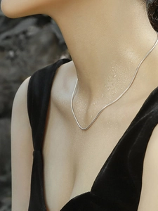 Close-up of a minimalist 1mm silver snake chain necklace on model with water drops