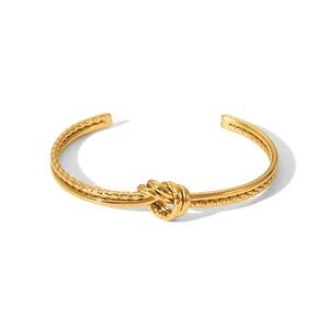 Nahaufnahme eines goldenen Knotenkordel-Armreifs mit polierter Oberfläche auf weißem Grund